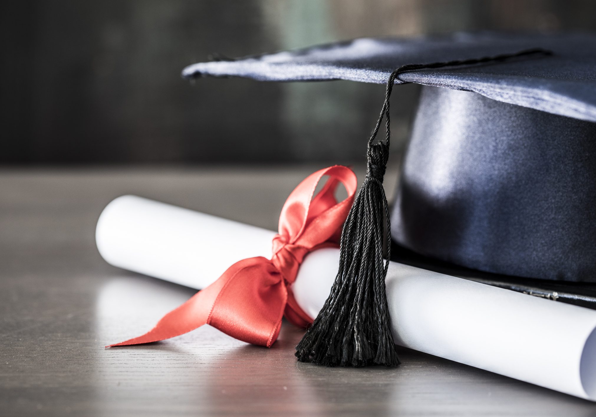 Graduation hat and diploma on table